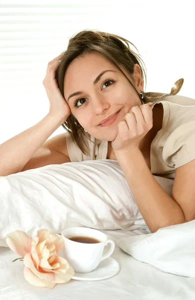 Junge kaukasische Frau liegt mit Tasse im Bett — Stockfoto