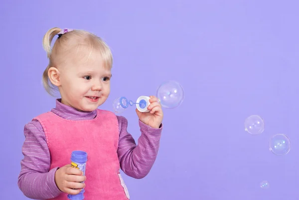 A small charming good Caucasian girl plays with bubbles — Stock Photo, Image