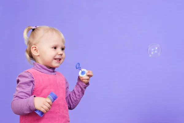 Una pequeña y encantadora marioneta caucásica juega con burbujas —  Fotos de Stock