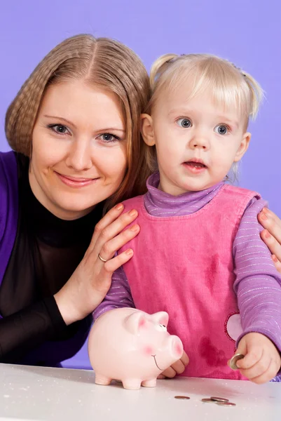Pretty Caucasian mama with her daughter play with the piggy bank — Stock Photo, Image