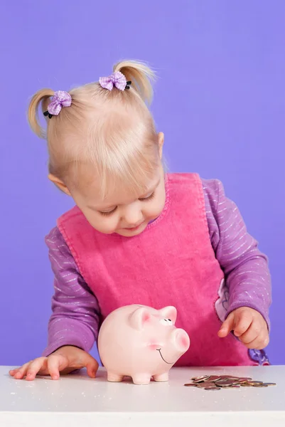 A small charming Caucasian girl plays with moneybox — Stock Photo, Image