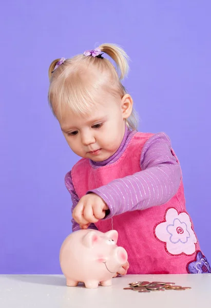 Een kleine charmante Kaukasische baby speelt met moneybox — Stockfoto