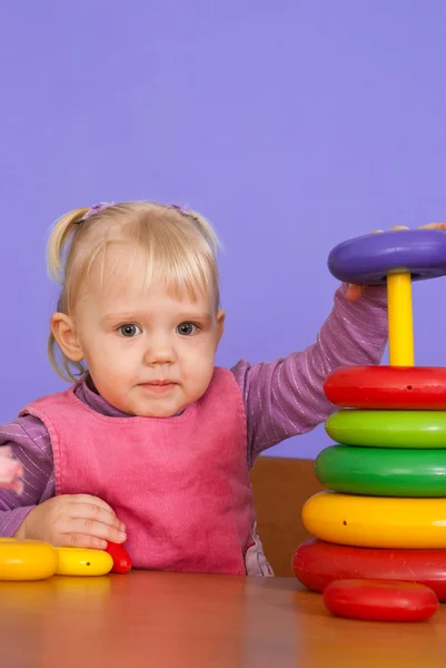 A small charming Caucasian toddler sitting at the table and play — Stock Photo, Image