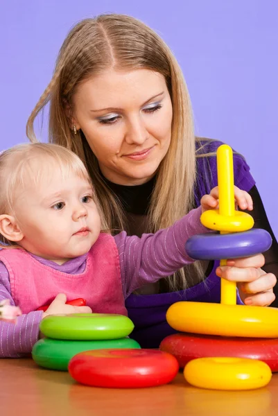 Pretty Caucasian mummy with her daughter play with a pyramid — Stock Photo, Image