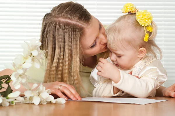 Mooie Kaukasische moeder en geluk dochter zitten aan een tafel — Stockfoto
