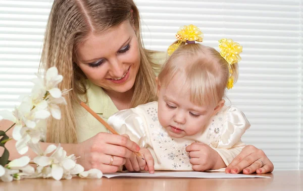 Beautiful Caucasian mother and luck daughter sitting at a table — Stock Photo, Image