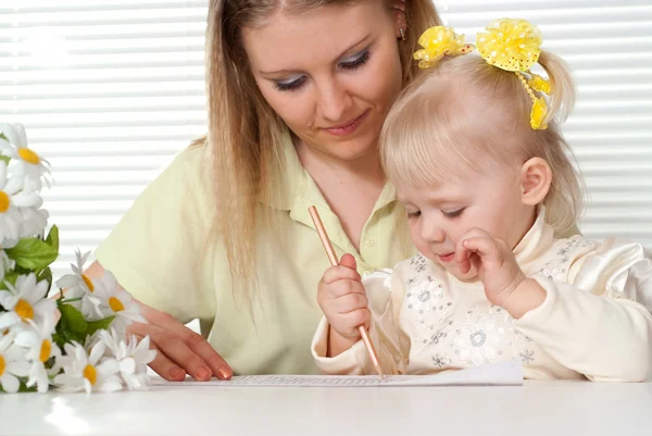 Beautiful Caucasian mother and luck daughter sitting at a table — Stock Photo, Image