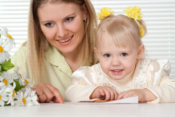 Beautiful Caucasian mother and bliss daughter sitting at a table — Stock Photo, Image