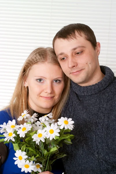 Lyckliga kaukasisk par med blommor står — Stockfoto
