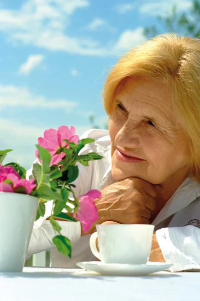 Beautiful Caucasian elderly woman sitting with a flower — Stock Photo, Image