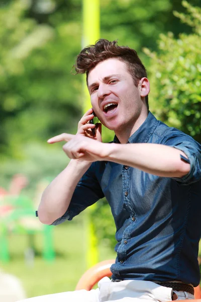 Młody człowiek w parku rozmów na telefon — Zdjęcie stockowe