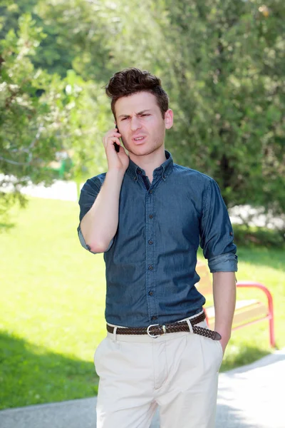 Hombre infeliz en el parque en el teléfono — Foto de Stock