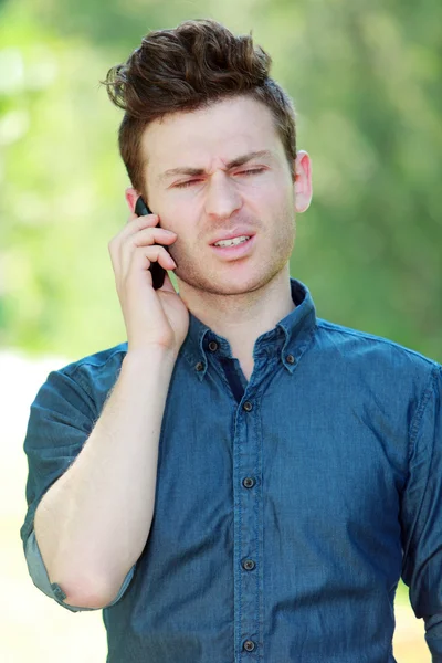 Απογοητευμένος νεαρός άνδρας στο τηλέφωνο — Φωτογραφία Αρχείου