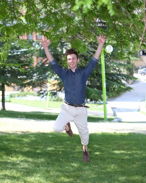Счастливый и прыгающий молодой человек в парке — стоковое фото