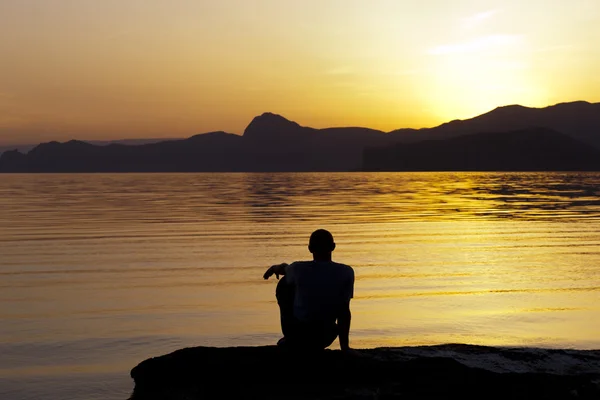 stock image Silhouette of sitting man at the sea in evening