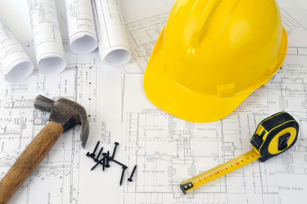 Yellow hard hat and heap of project drawings — Stock Photo, Image
