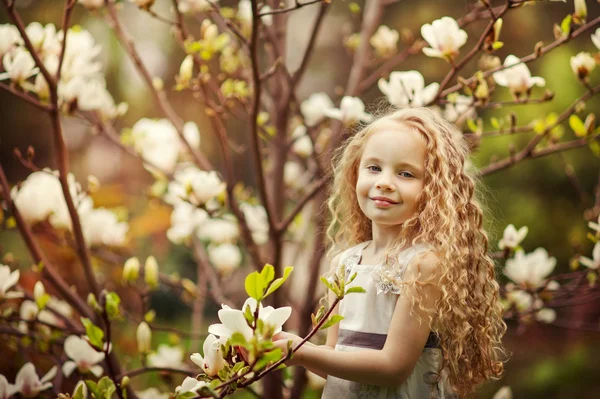 Menina bonita e árvore de magnólia florescente — Fotografia de Stock