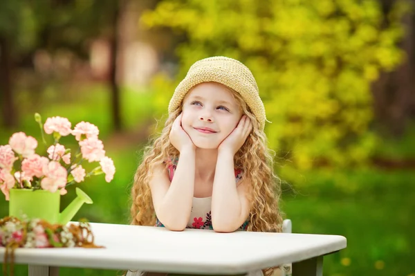 Liten flicka i trädgården med blommor — Stockfoto