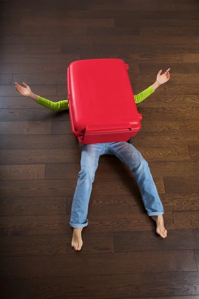 Lying woman under red suitcase — Stock Photo, Image