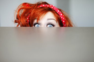 Funny girl hiding behind a table