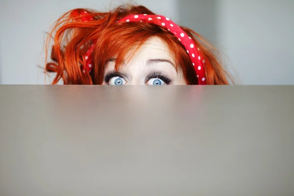 Menina engraçada se escondendo atrás de uma mesa Fotografia De Stock