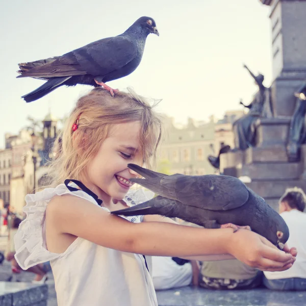 Menina sorridente com pombo na cabeça e nos braços — Fotografia de Stock