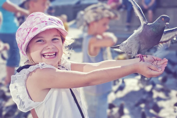 Smiling girl feeding pigeon — Stock Photo, Image
