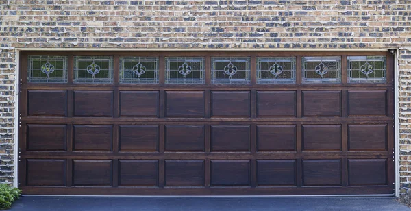 Porta de garagem de madeira escura com fundo de parede de tijolo — Fotografia de Stock