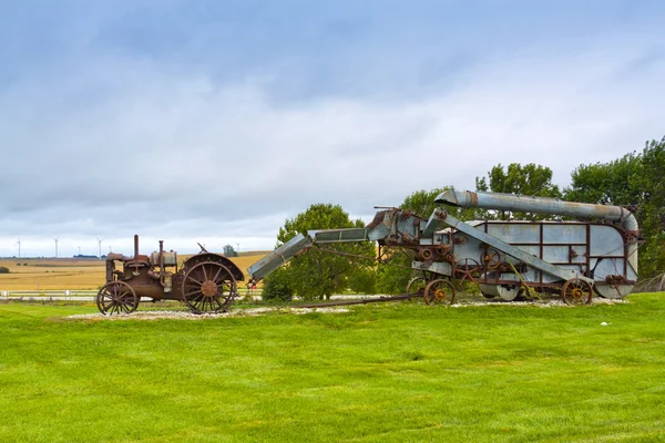 Gamla rostiga traktorn med vindkraftverk i bakgrunden. — Stockfoto