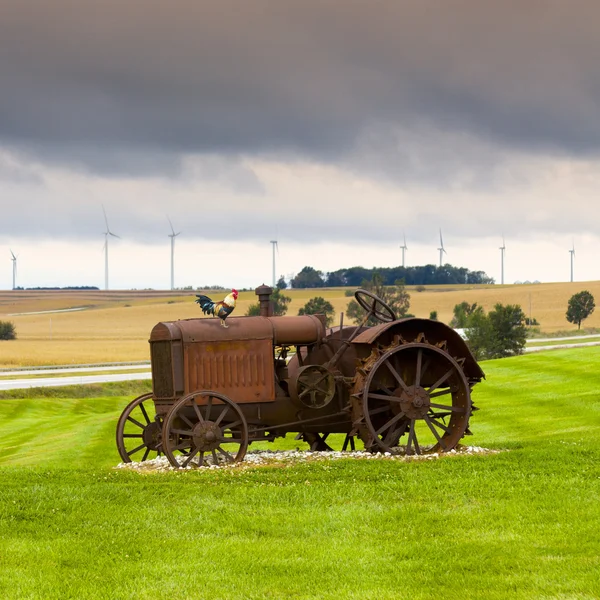 Old rusty tractor with wind turbines in the background. — Stock Photo, Image