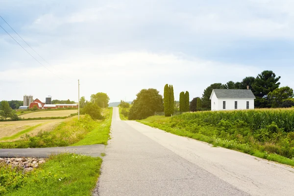 Сільська дорога з червоним ферми і церква — стокове фото