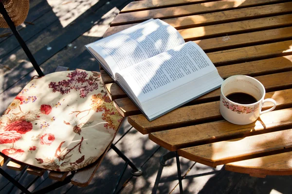Boek en koffie op houten tafel — Stockfoto
