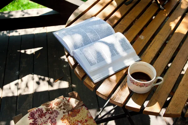Boek en koffie op houten tafel — Stockfoto