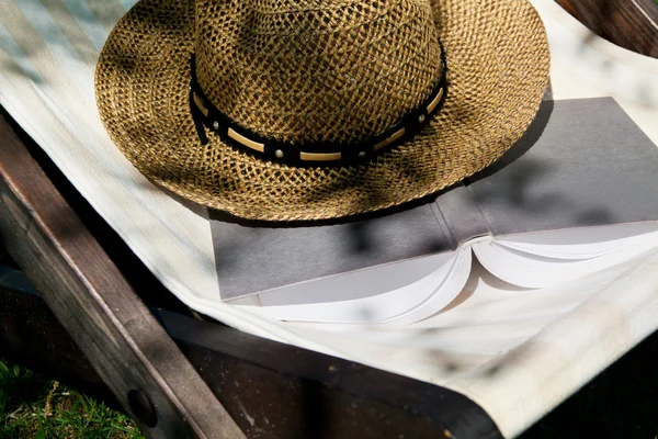 Boek en stro hoed op strandstoel — Stockfoto