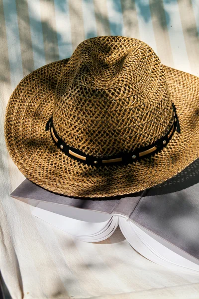 Livro e chapéu de palha na cadeira de praia — Fotografia de Stock