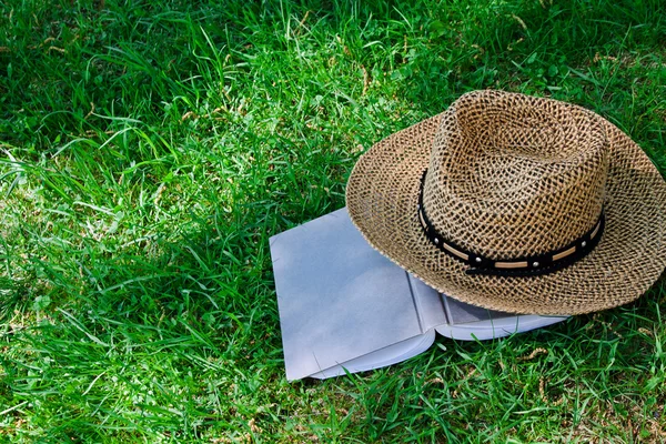 Livro e chapéu de palha na grama — Fotografia de Stock