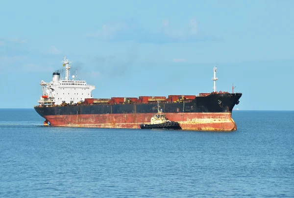 Tugboat assisting cargo ship — Stock Photo, Image
