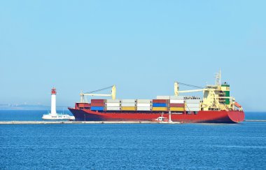 Cargo ship near lighthouse clipart