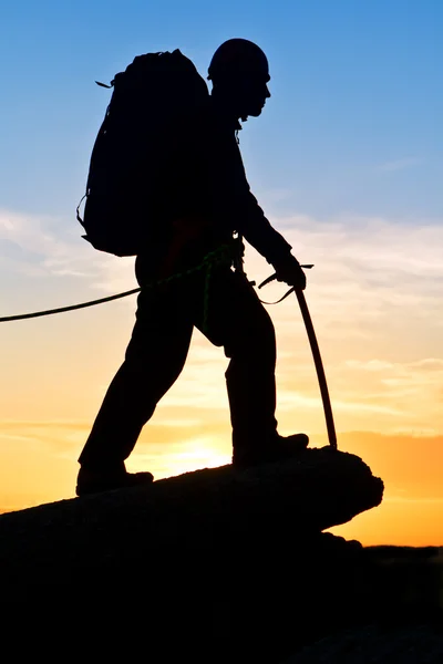 Silhouette climber with an ice axe at mountain top — Stock Photo, Image