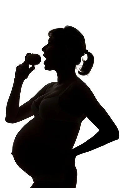 Беременная девушка ест яблоко — стоковое фото