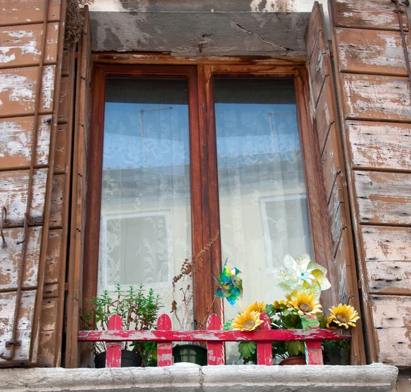 Gammalt fönster med fönsterluckor och blommor — Stockfoto