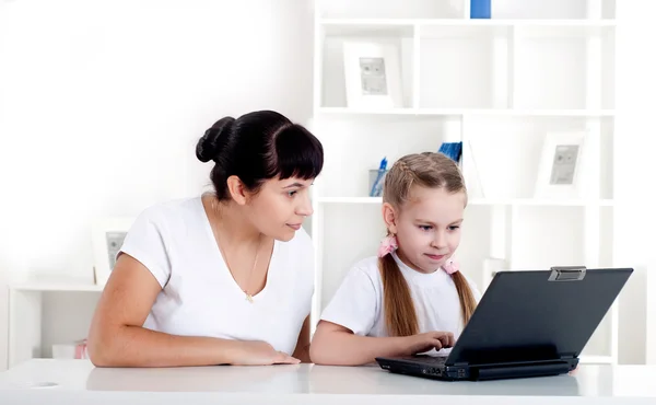 Mãe e filha estão trabalhando juntas para um laptop — Fotografia de Stock