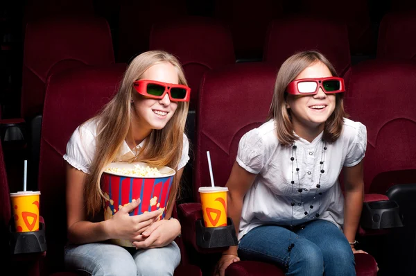 Two beautiful girls watching a movie at the cinema — Stock Photo, Image