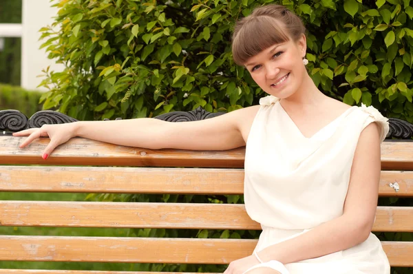 A beautiful woman is sitting on a park bench — Stock Photo, Image