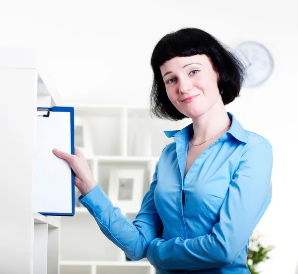 Mulher coloca um tablet com documentos em prateleiras — Fotografia de Stock
