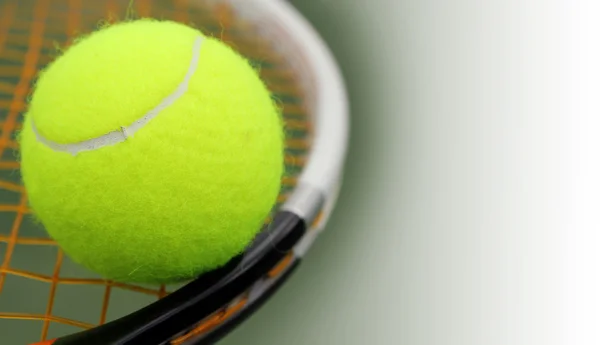 New tennis ball on a new racket with orange string(gut) and the — Stock Photo, Image
