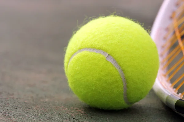 Nova bola de tênis de cor amarela colocada ao lado de raquete (raquete) em — Fotografia de Stock