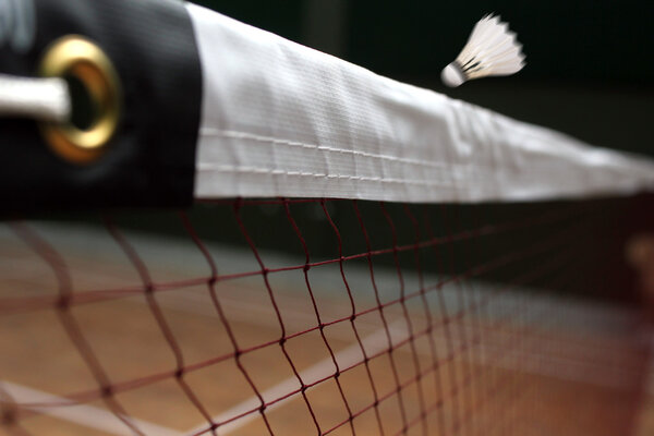Photo of shuttle badminton net up close and a fast moving shuttl