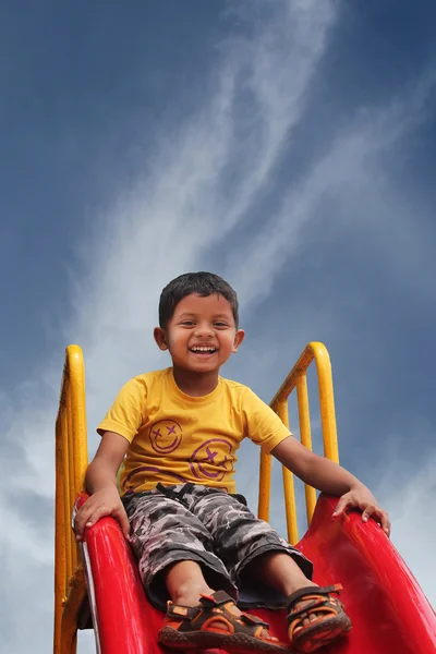 Gelukkig lachend en knappe Indiase kind plezier spelen gleed — Stockfoto