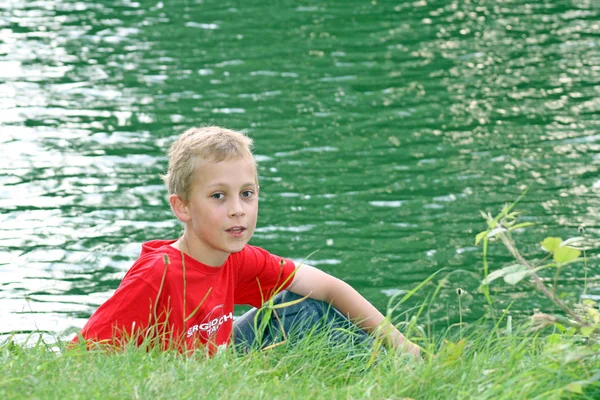 Genç çocuk bir göl kenarında oturdu — Stok fotoğraf